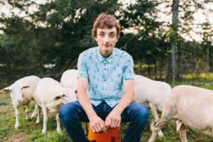 Maine highschool senior portrait by kerry struble, NH portrait artist. on the farm senior photos with sheep in background.